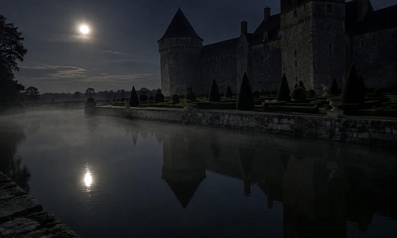 Le miroir d'eau sous la lune, quand la brume s'installe entre les douves et les ifs taillés.